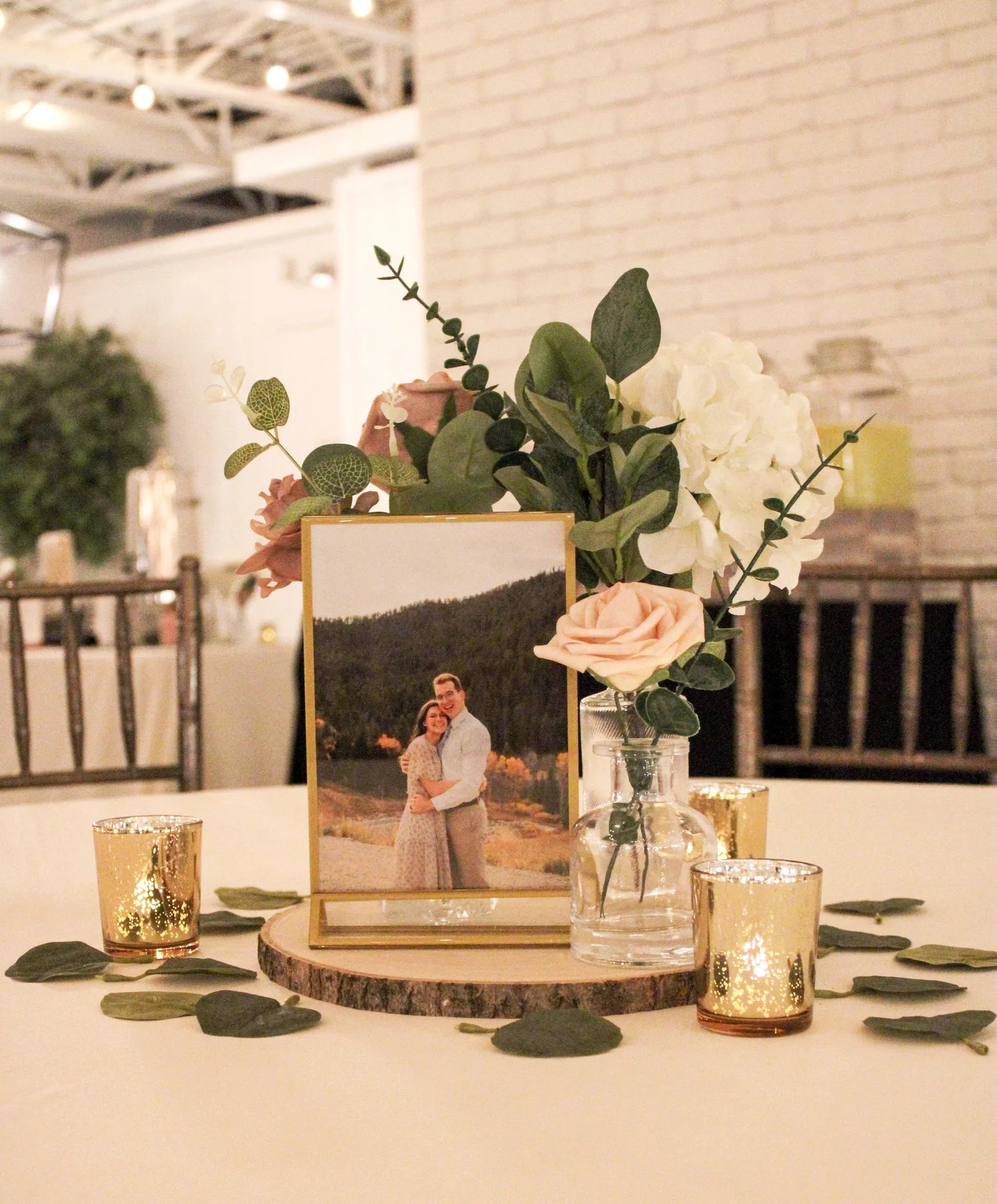 Reception table centerpiece with roses, candles and a framed couple photo