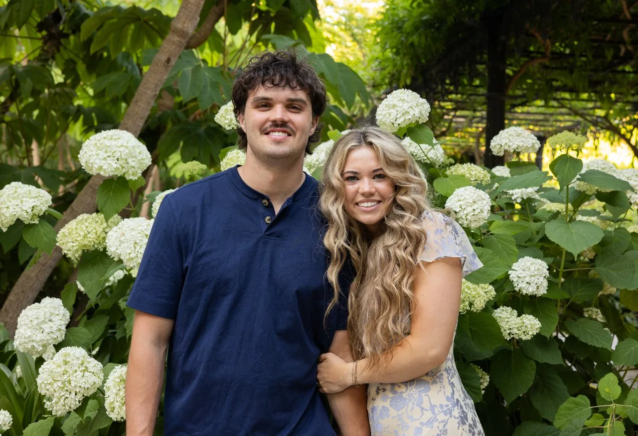 Smiling couple in front of white hydrangeas in a garden