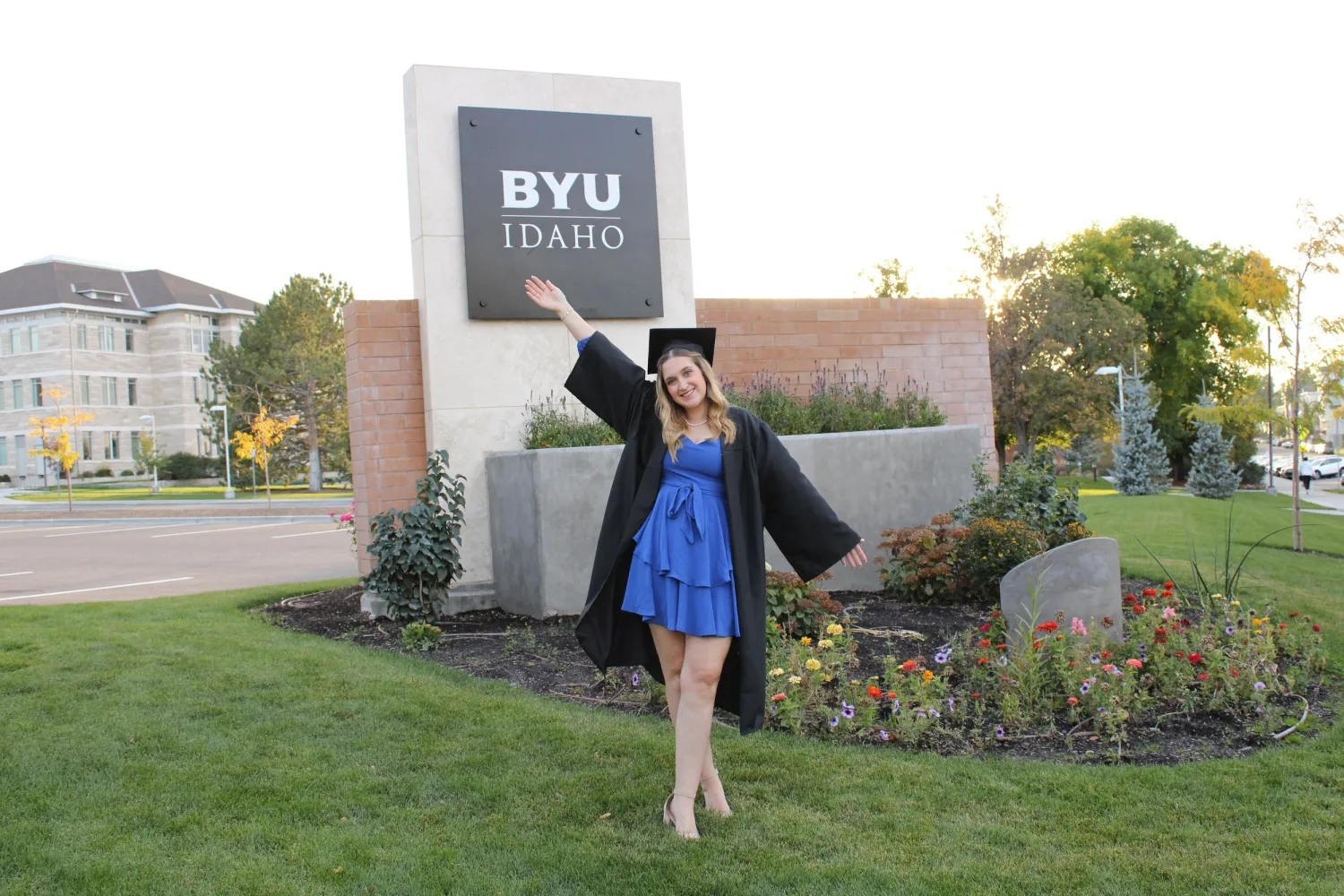 BYU-Idaho graduate in cap and gown celebrating in front of the BYU-Idaho sign
