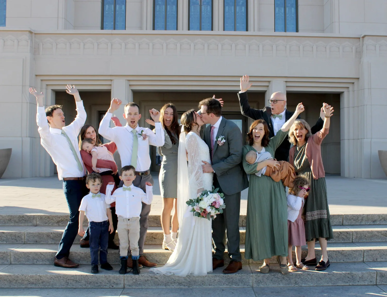 Wedding party cheering with the bride and groom on the temple steps