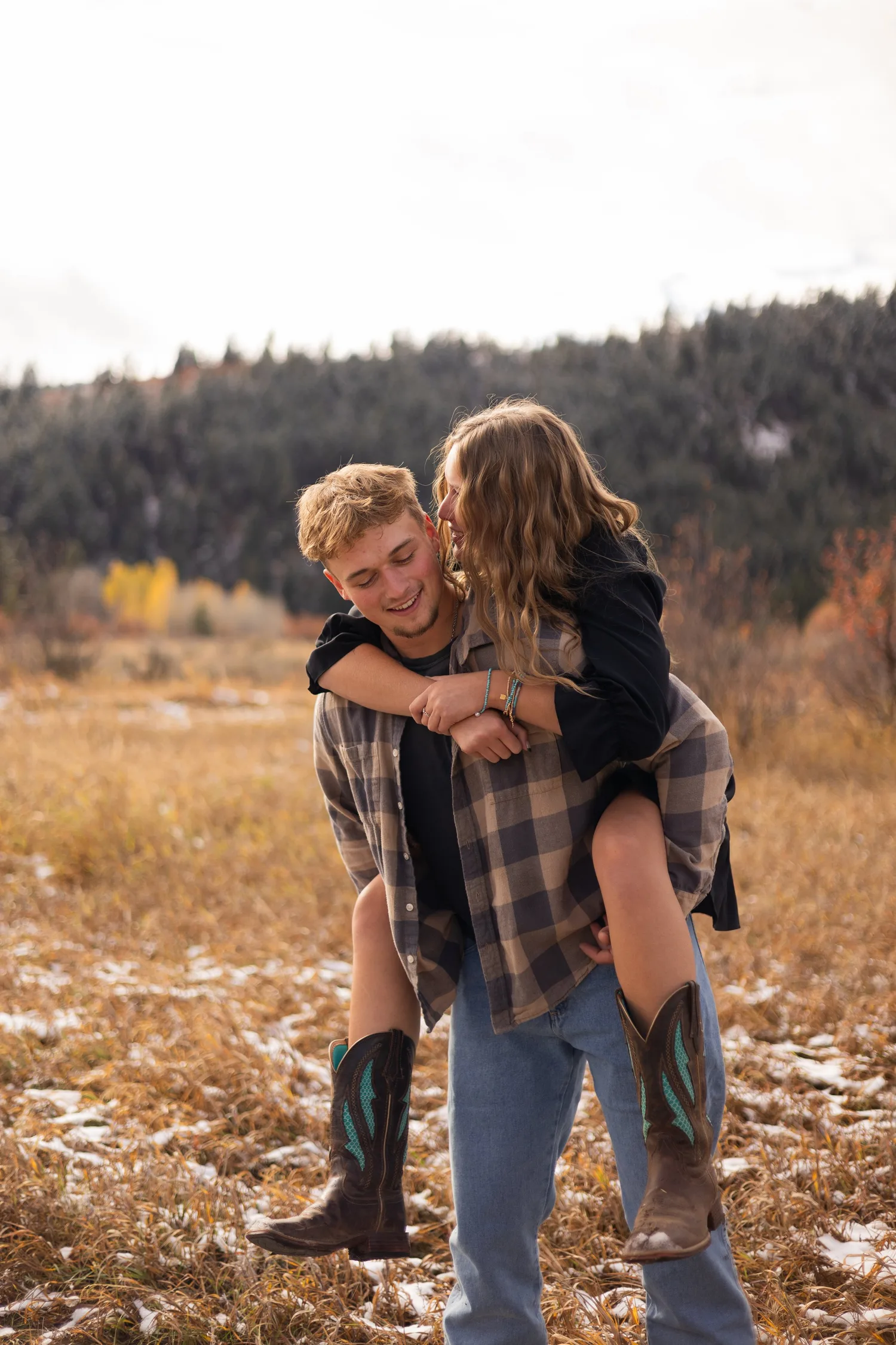 Man carrying his laughing girlfriend piggyback in an autumn field