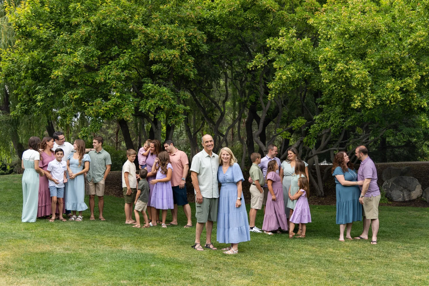 Extended family group portrait on a lawn beneath large trees