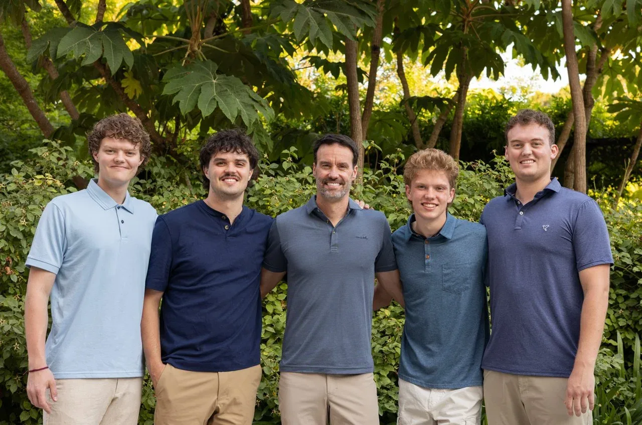 Father with his four sons in front of green foliage