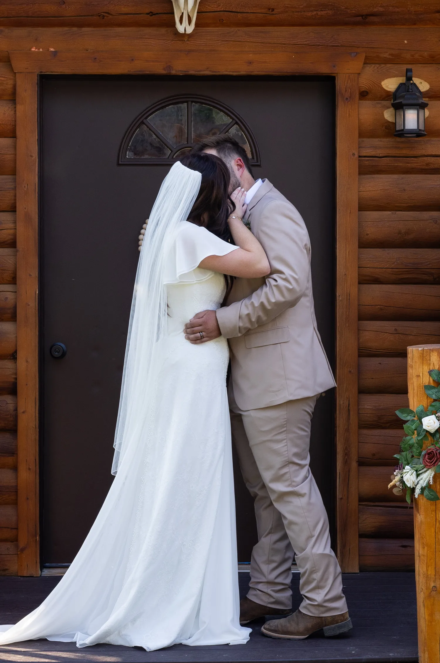 Bride and groom kissing in front of a log cabin door