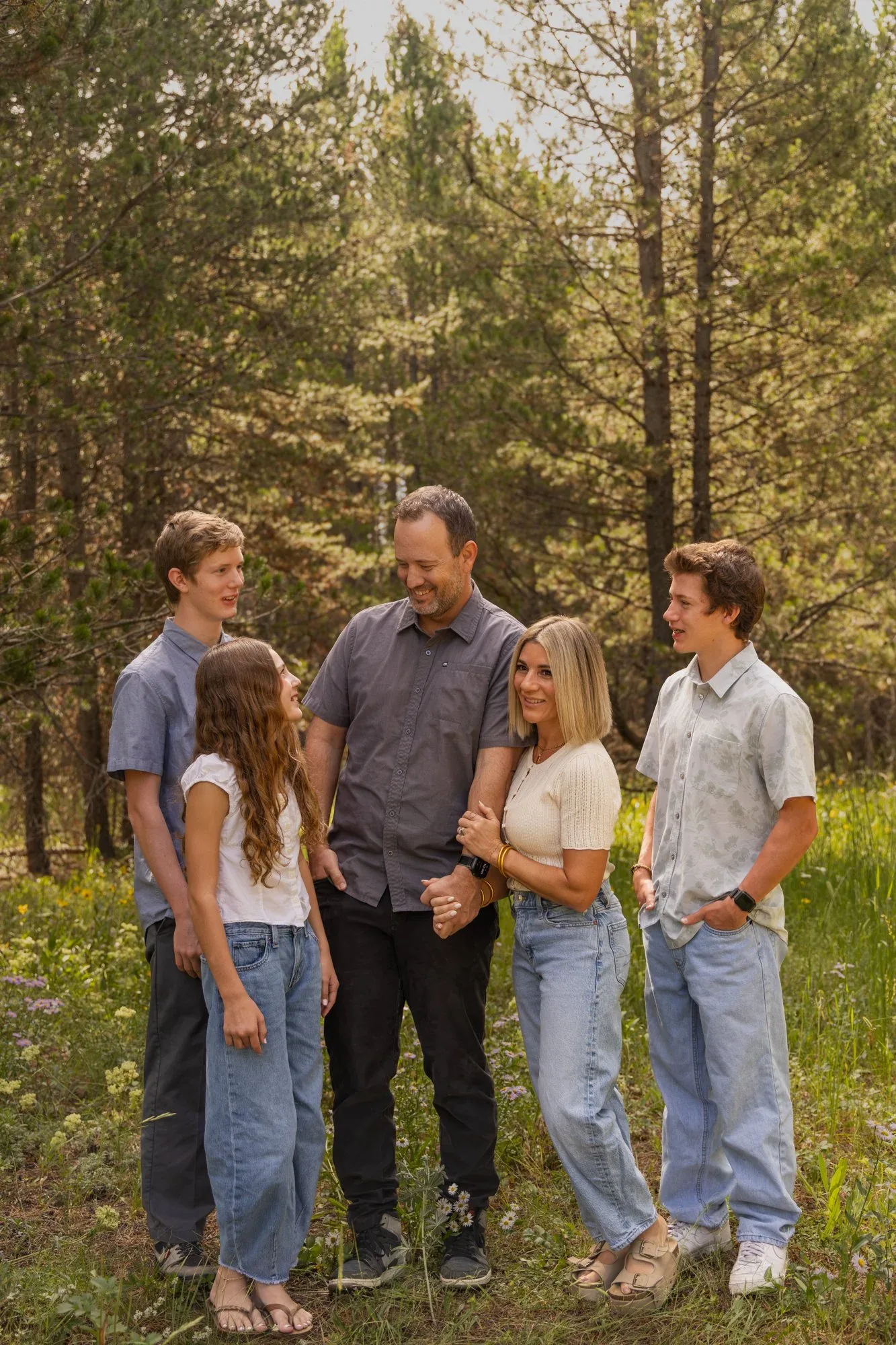 Family of five laughing together among pine trees