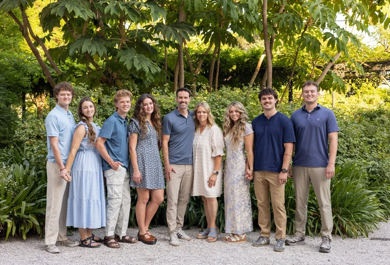 Large family of adult siblings and spouses posing in a garden