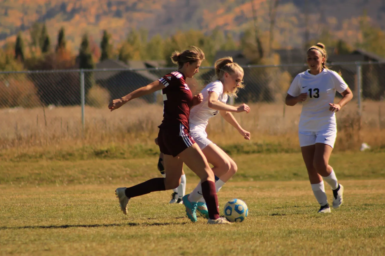 Soccer players battling for the ball on an autumn field