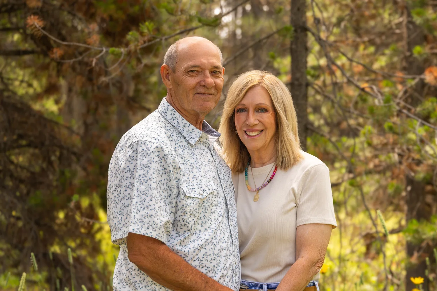 Smiling older couple embracing in front of autumn trees
