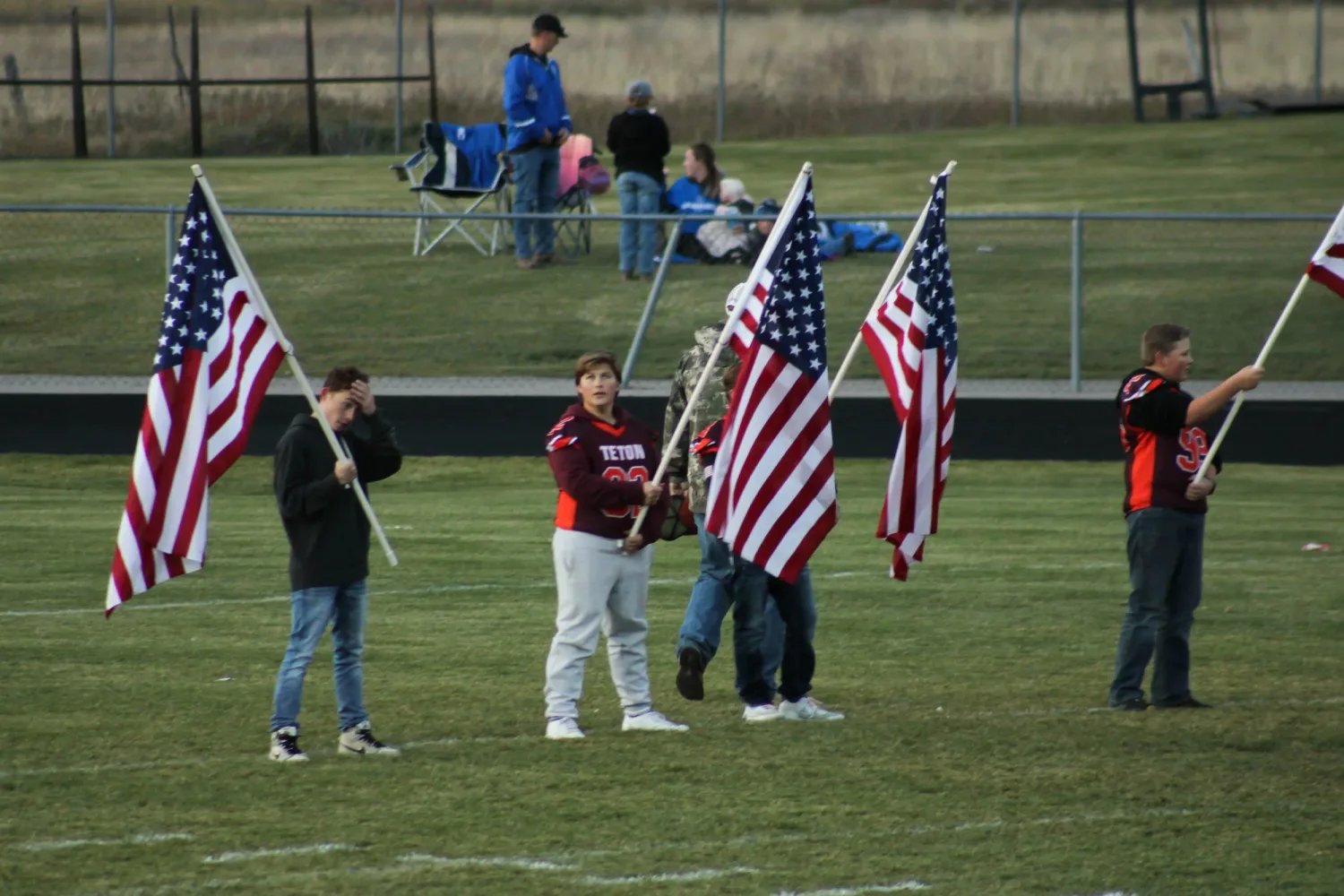 Flag bearers holding American flags on the field before a game