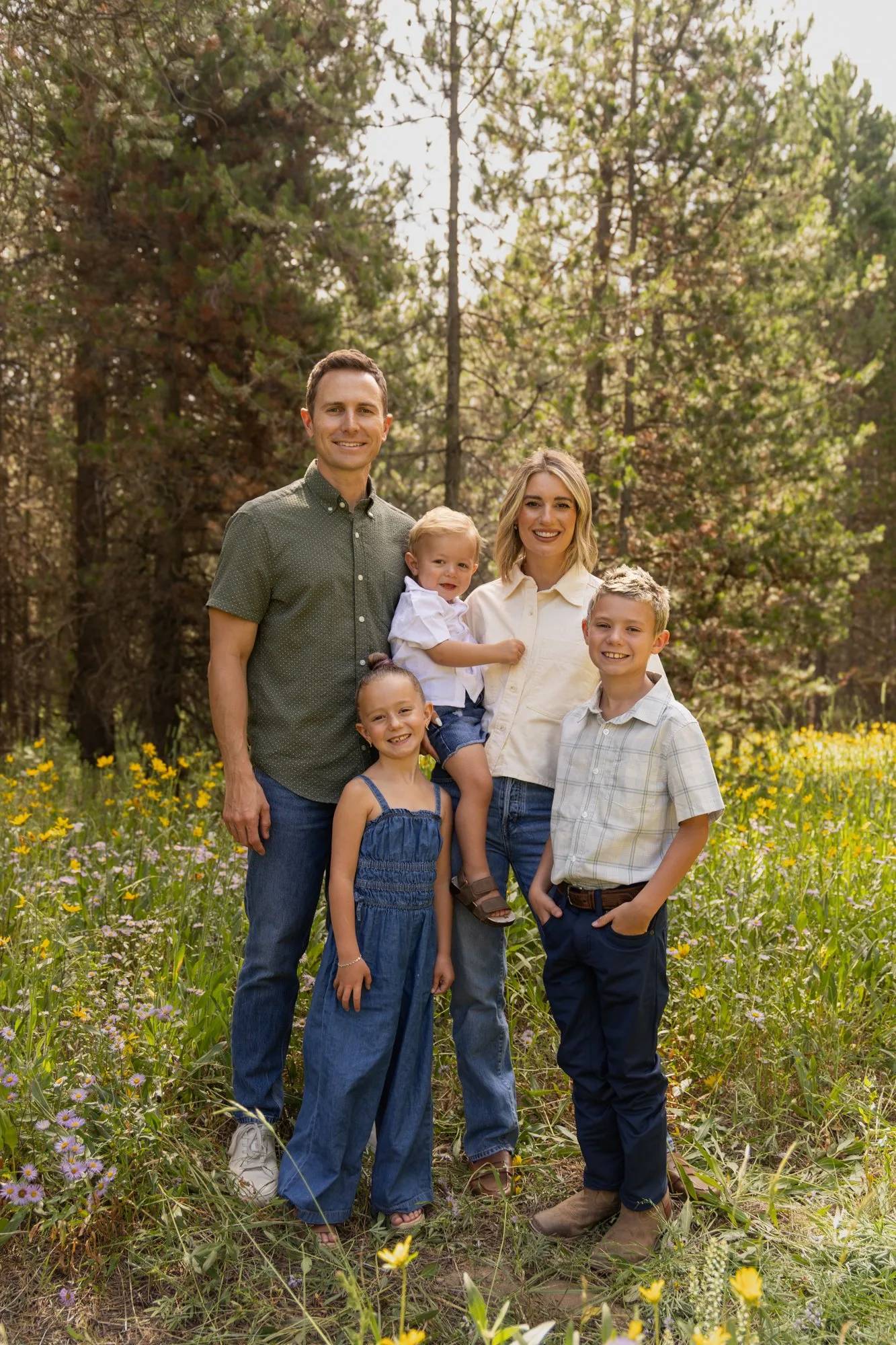 Family of five with a baby and toddler in a summer meadow among pines
