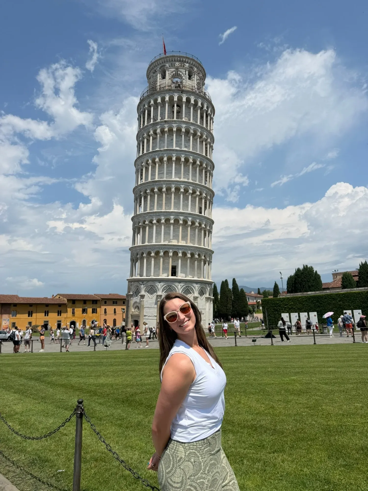 Woman in sunglasses posing in front of the Leaning Tower of Pisa