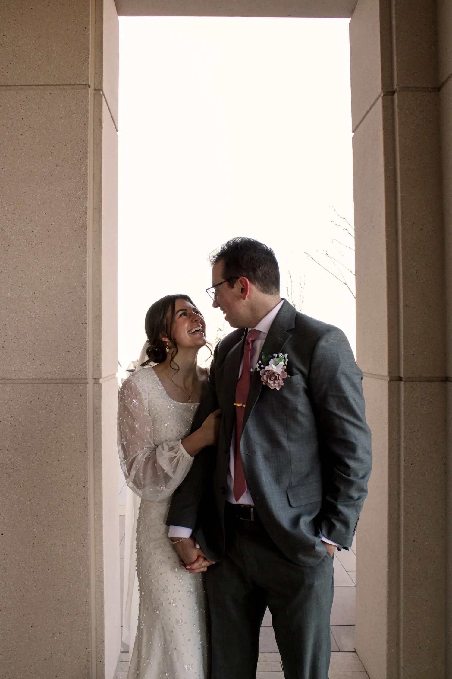 Bride and groom laughing together in a stone temple archway