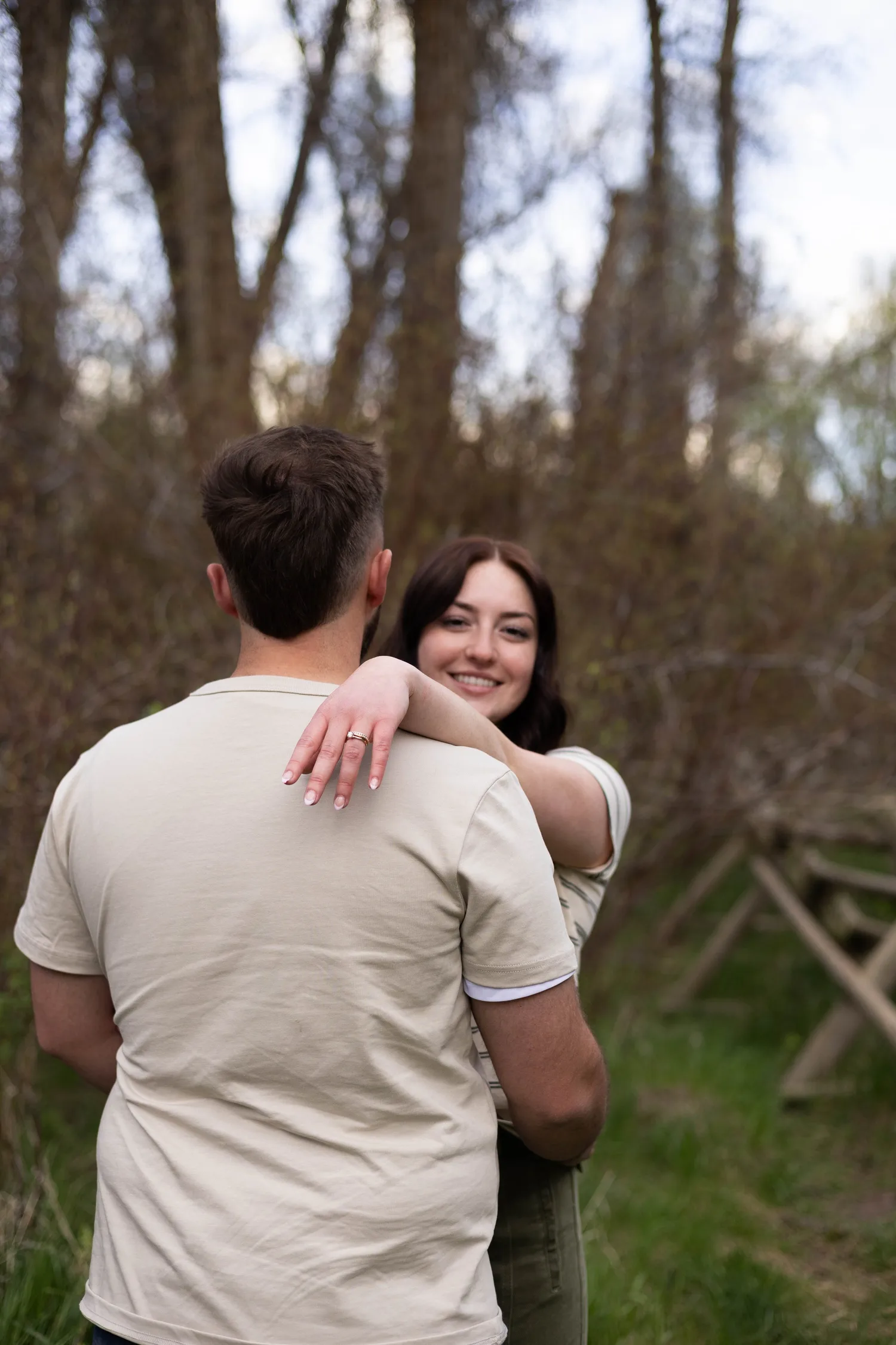 Woman hugging her fiancé and showing her engagement ring