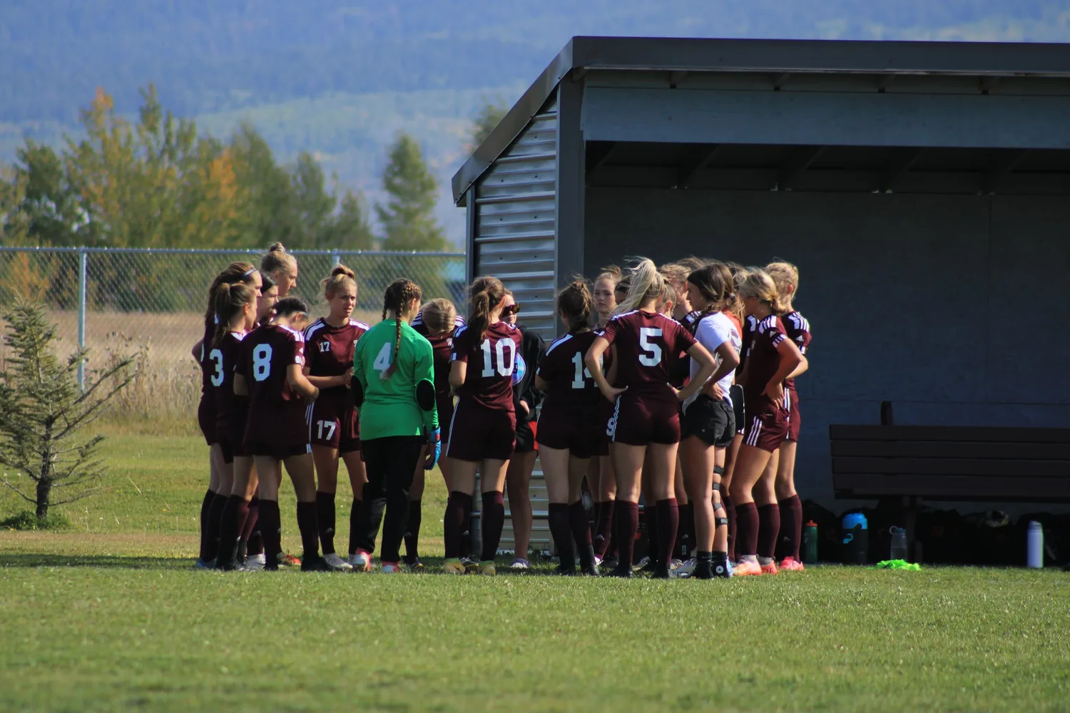 Girls' soccer team huddled together on the sideline
