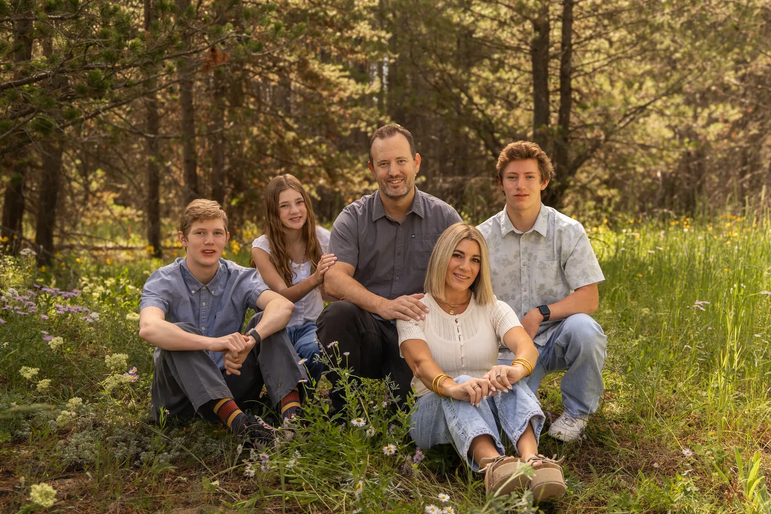 Family of five sitting together in a forest meadow