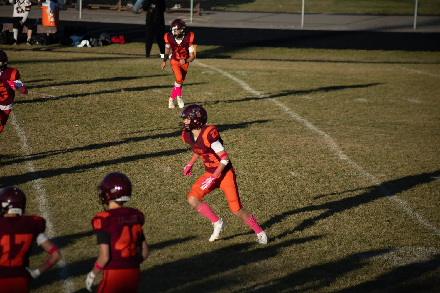 Youth football player running in pink socks for breast cancer awareness week