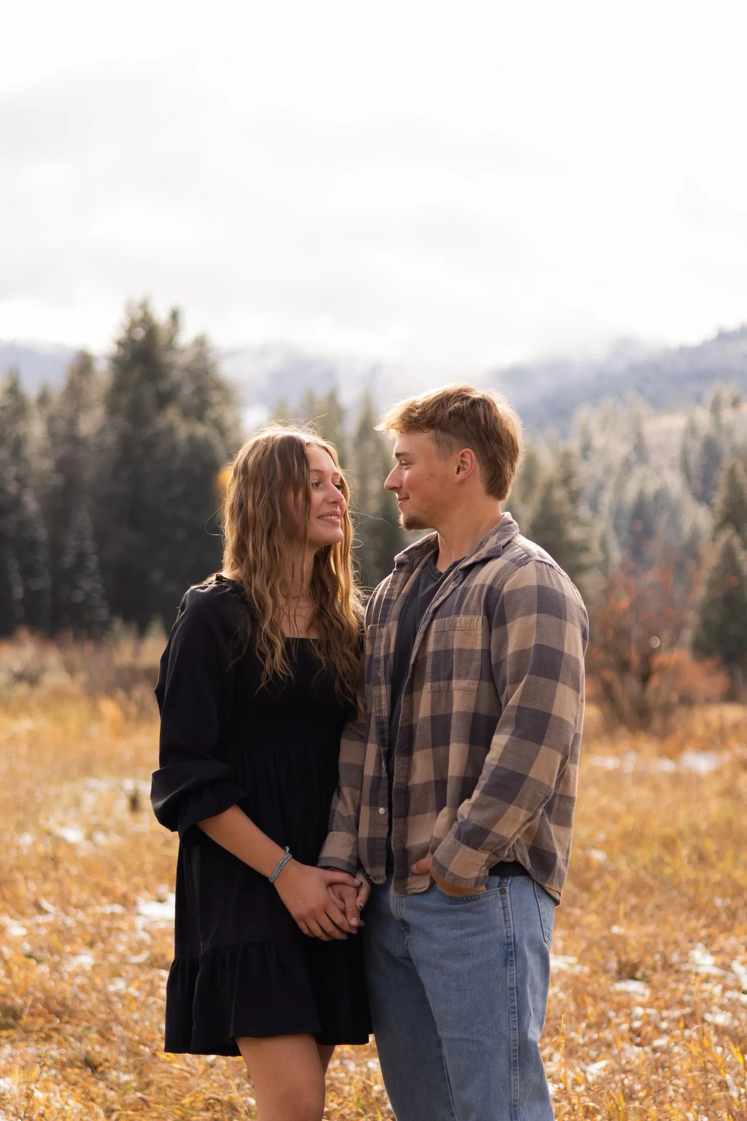 Couple holding hands and gazing at each other in an autumn meadow