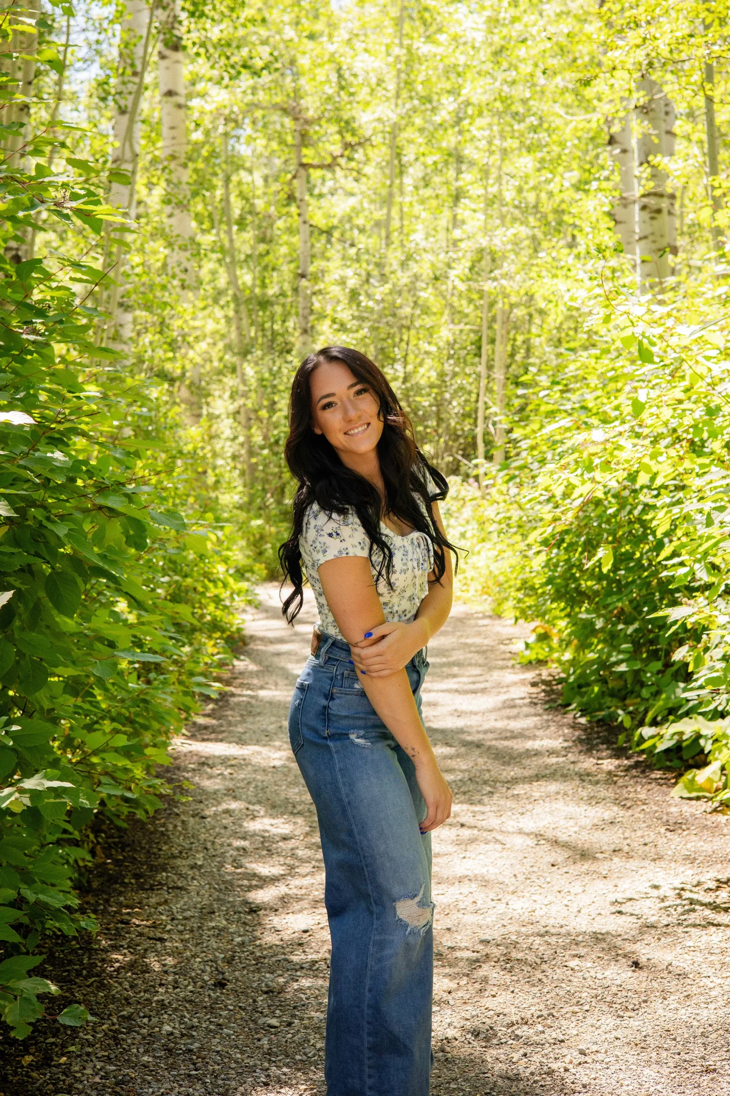Senior portrait of a young woman on a leafy forest path in summer