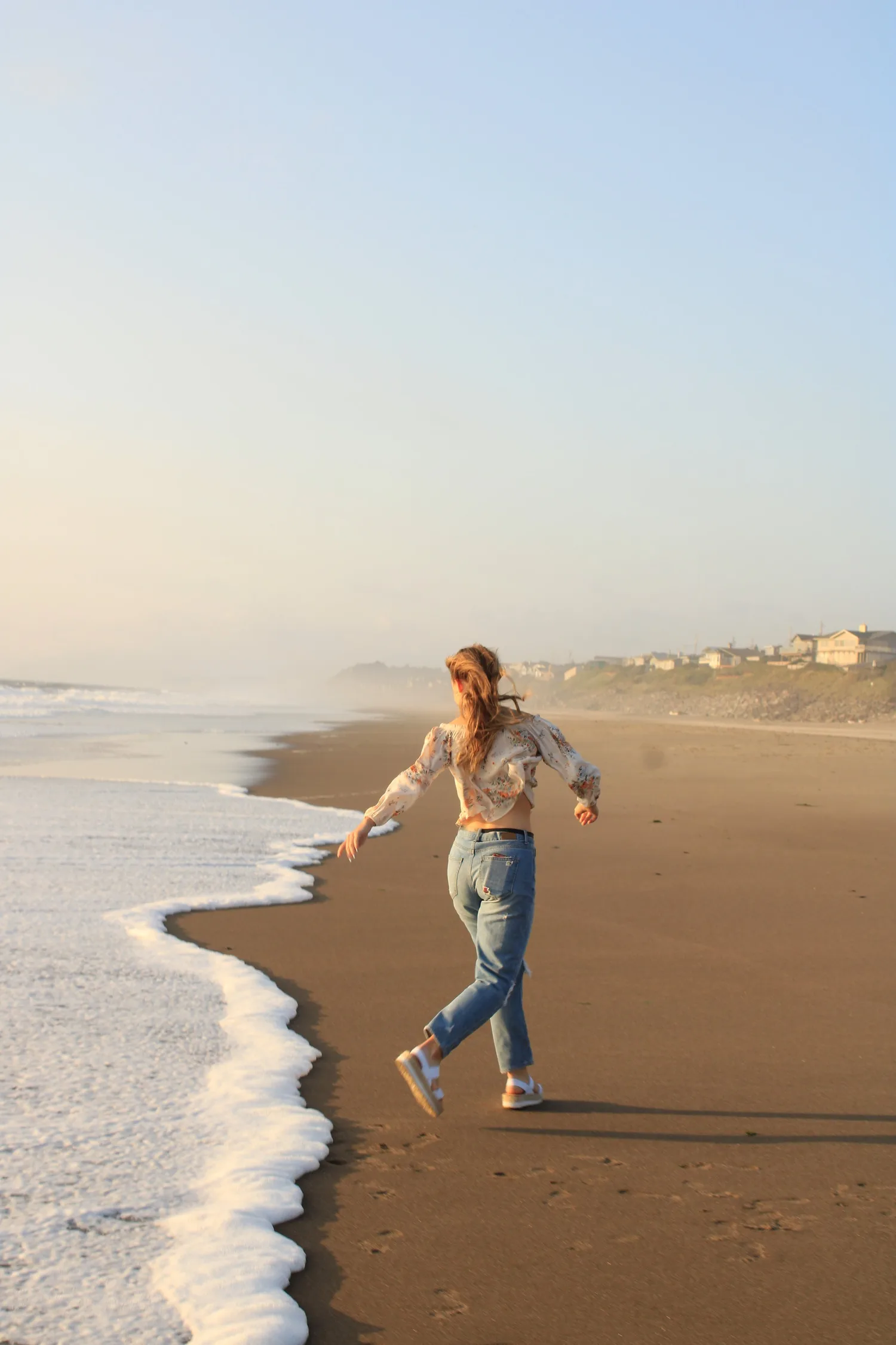 Young woman running along a sandy beach at the water's edge