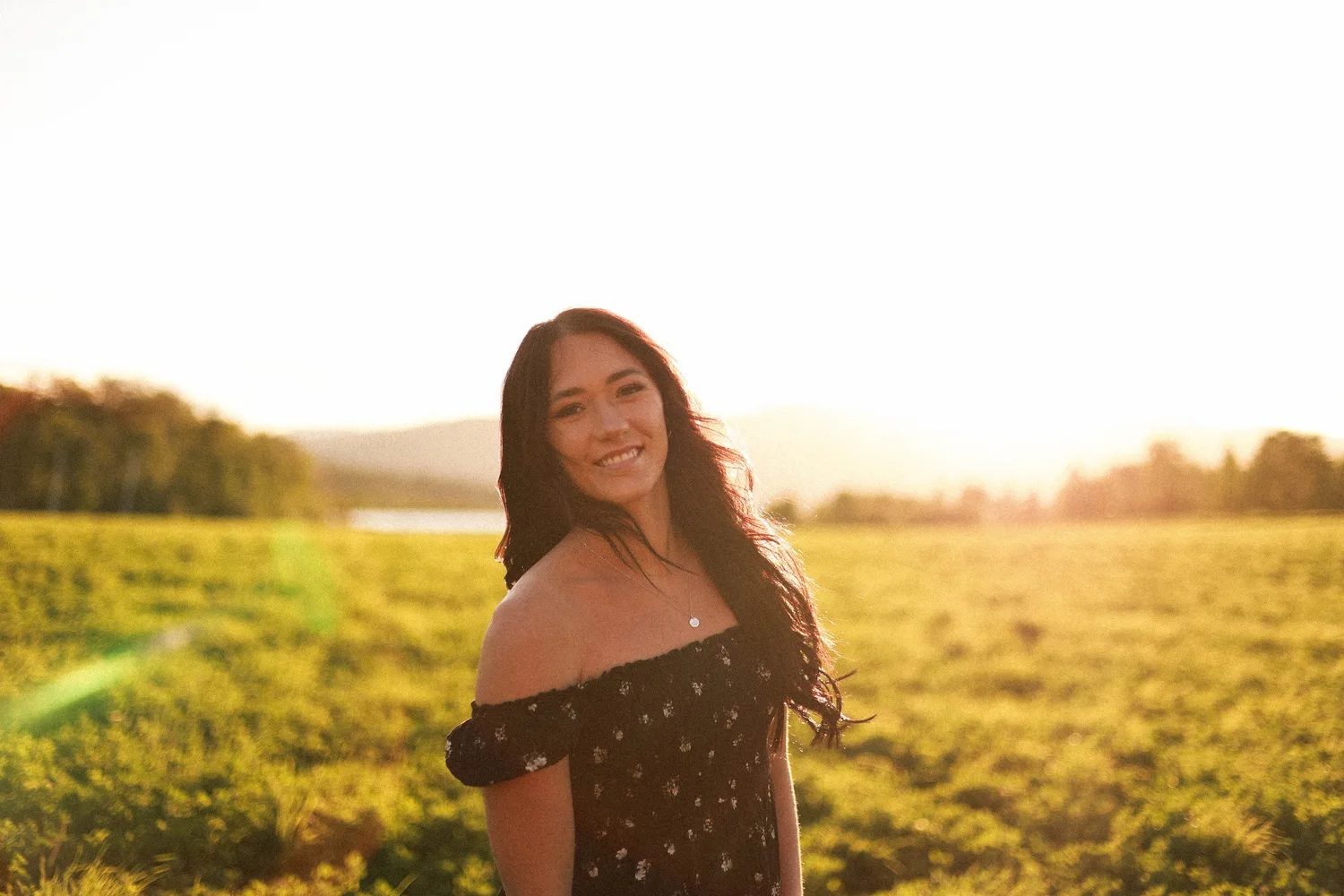 Young woman in an off-the-shoulder dress in a field at golden hour