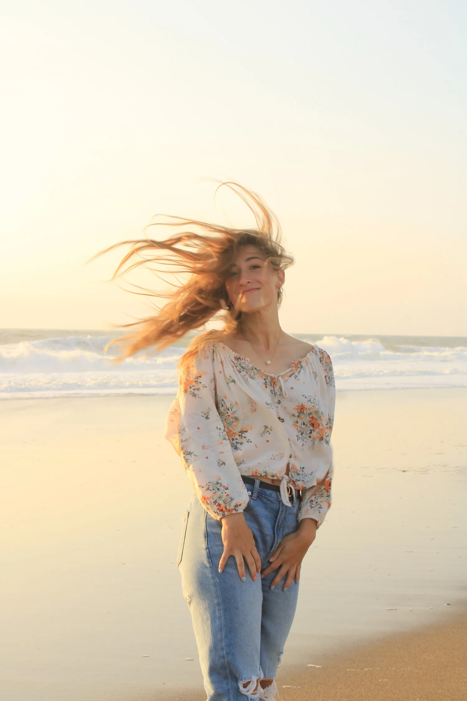 Young woman with windswept hair on the beach at golden hour