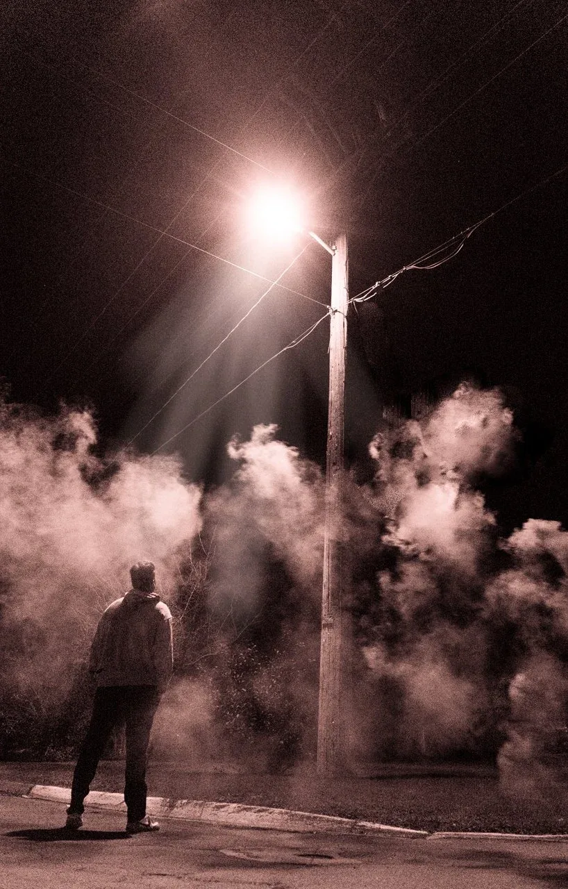Moody night portrait of a man under a streetlight surrounded by fog