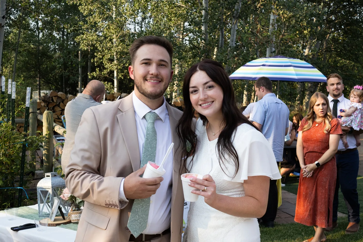 Bride and groom smiling with guests at their outdoor wedding reception