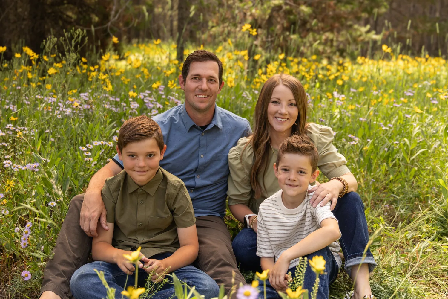 Parents and two sons sitting in a field of yellow wildflowers