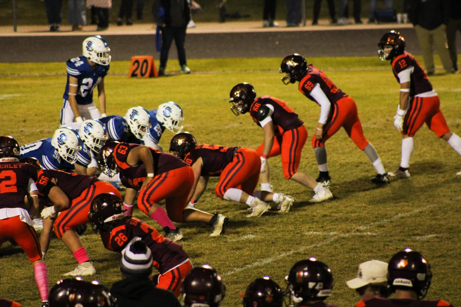 Youth football teams lined up for a snap during a night game