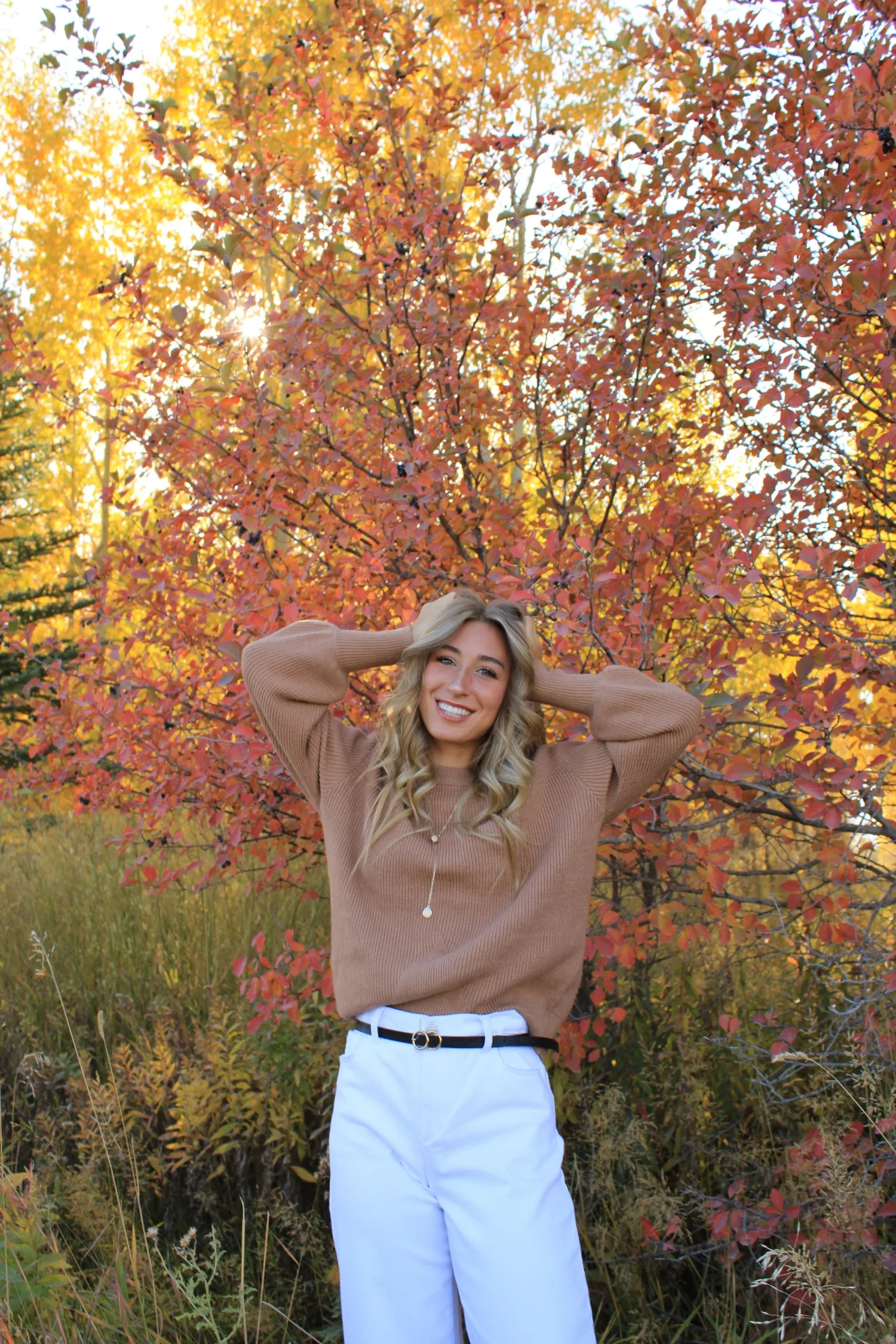 Senior portrait of a smiling young woman among bright red fall leaves