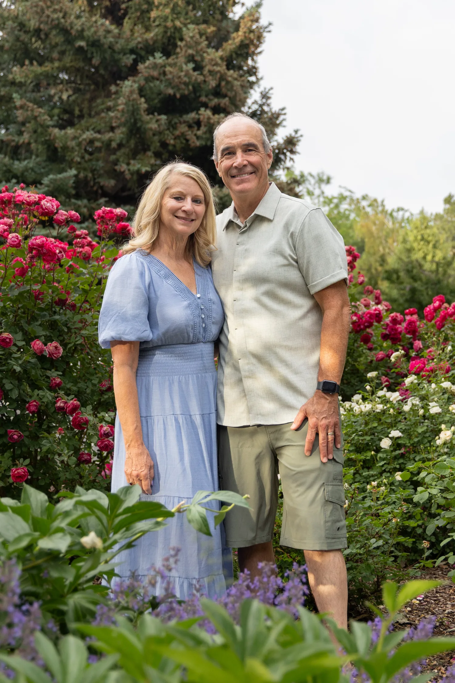 Older couple standing in a garden of pink peonies