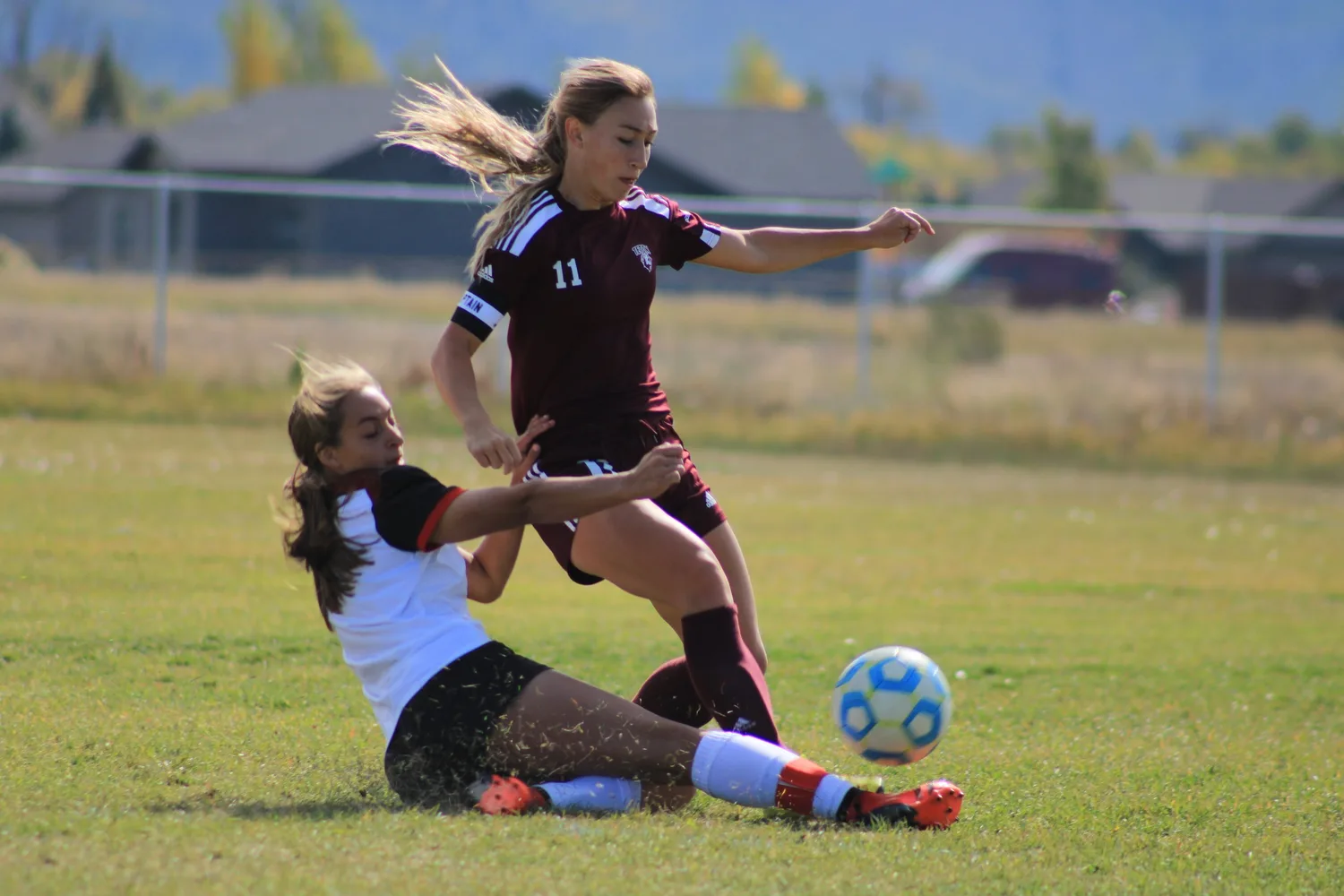 Girls' soccer players colliding during a slide tackle