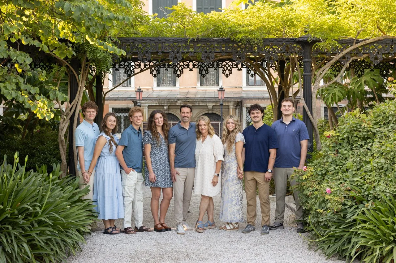 Extended family in blue outfits under a vine-covered pergola