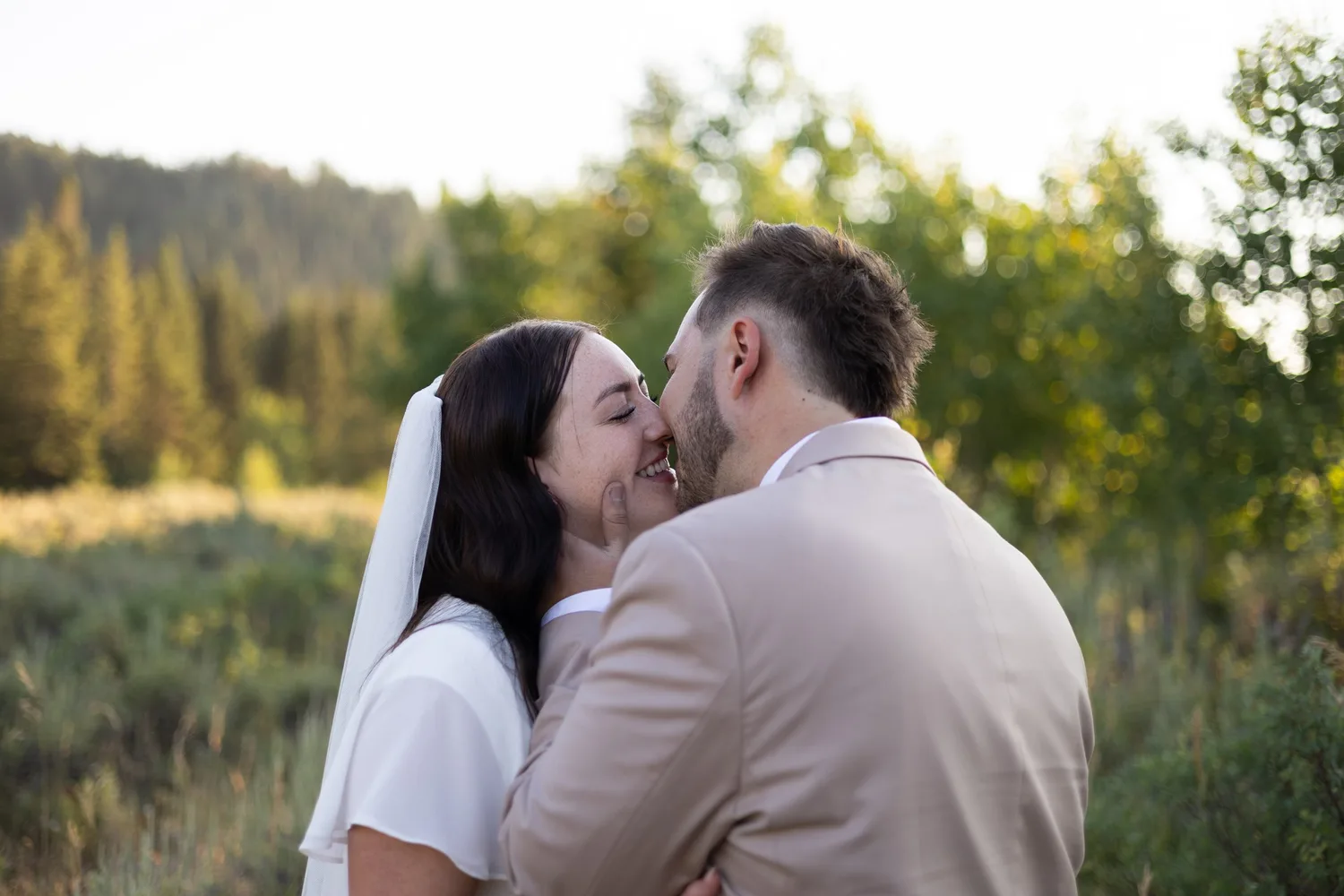 Close-up of the bride and groom kissing with a mountain forest behind them
