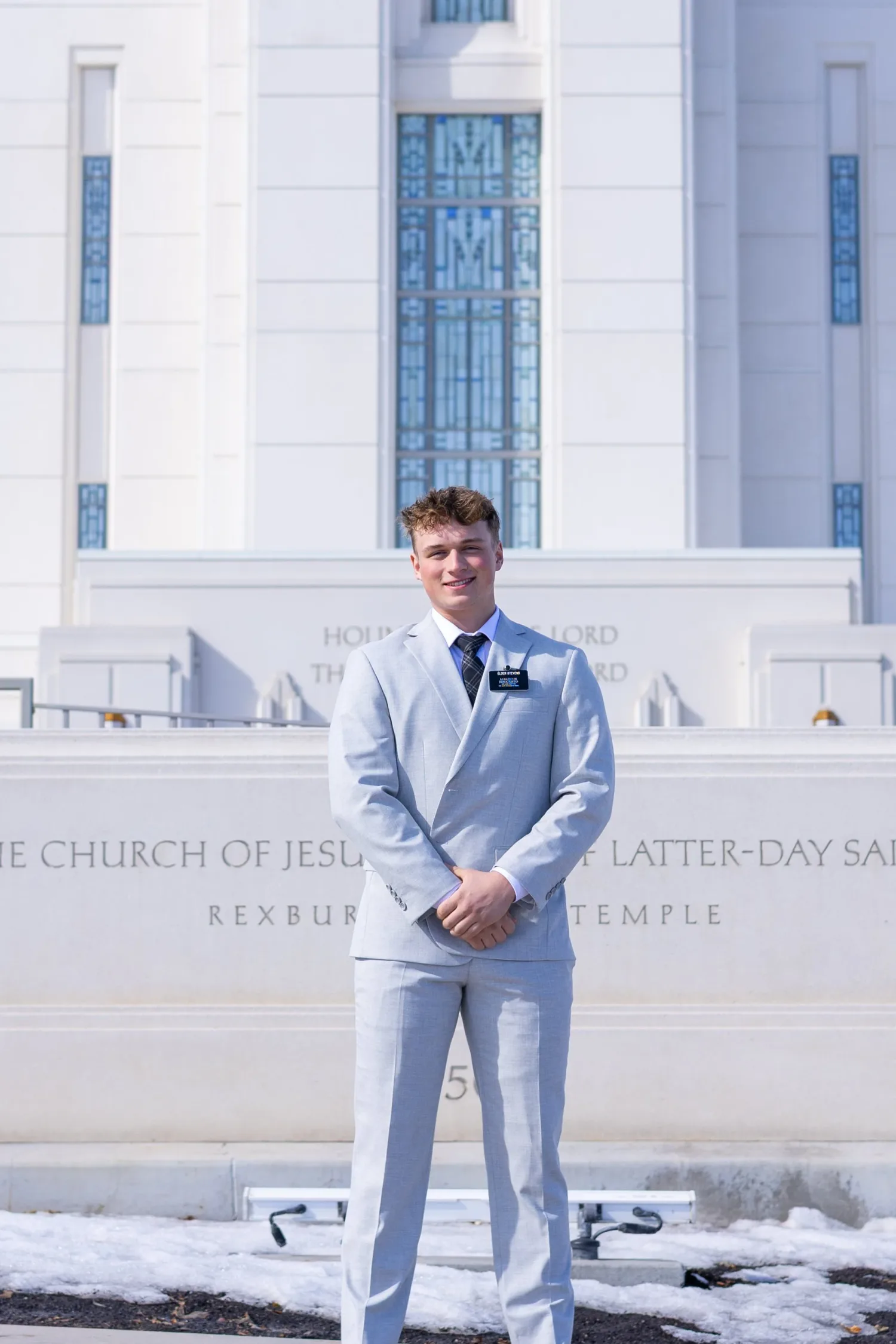 Missionary portrait in a light blue suit in front of the Rexburg Idaho Temple sign