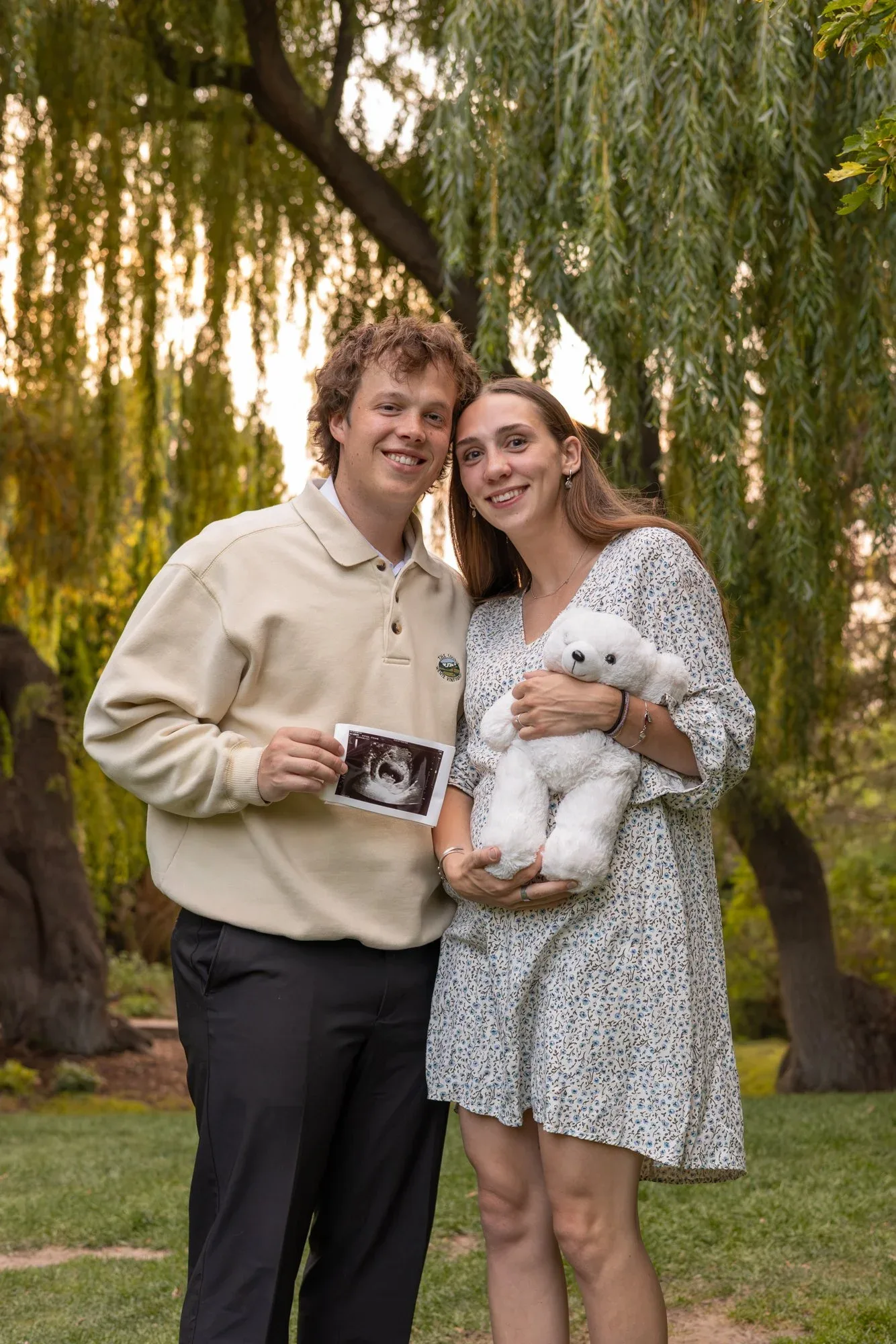 Expecting couple holding an ultrasound photo and a white teddy bear