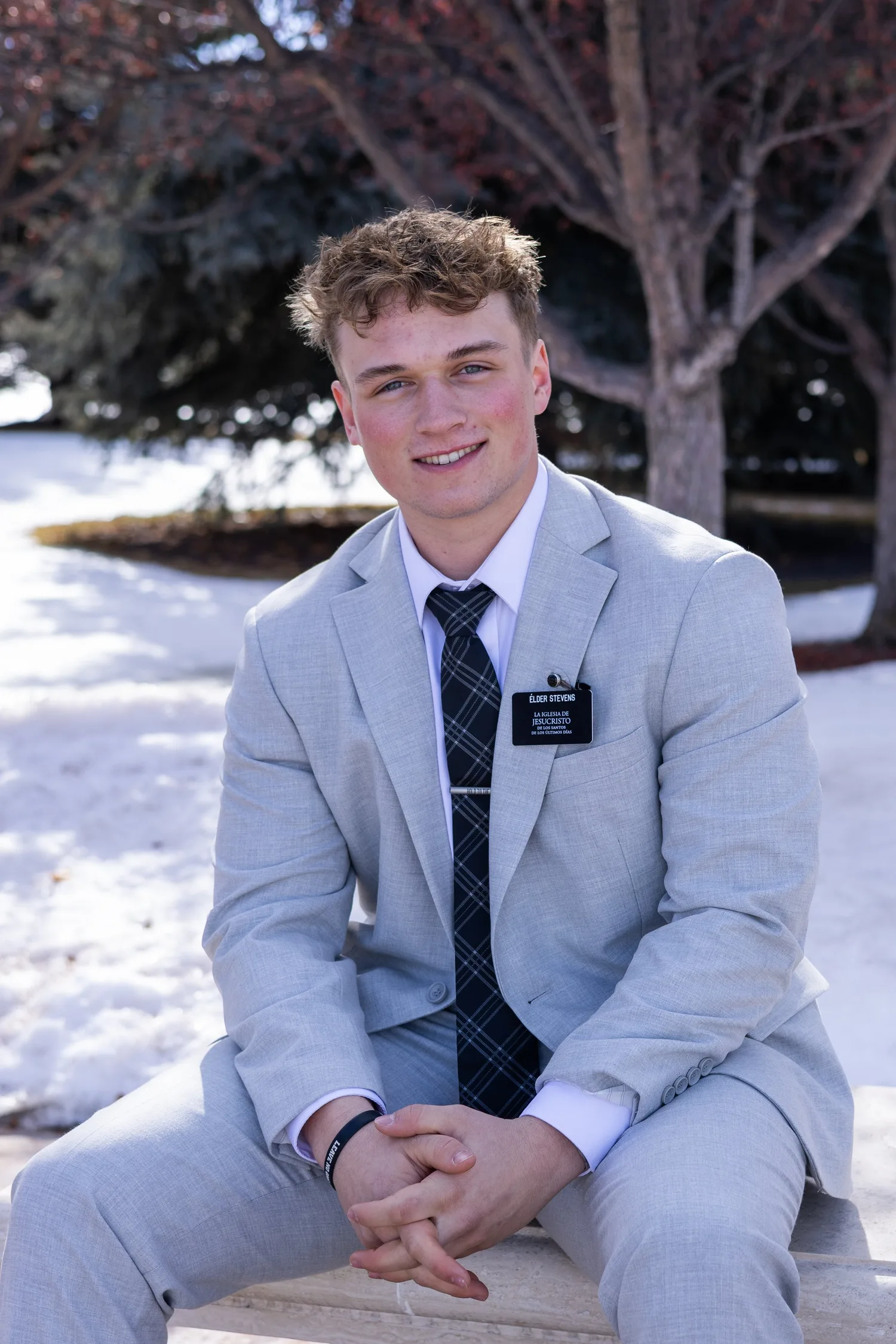 Missionary portrait of a smiling young man in a light gray suit in the snow