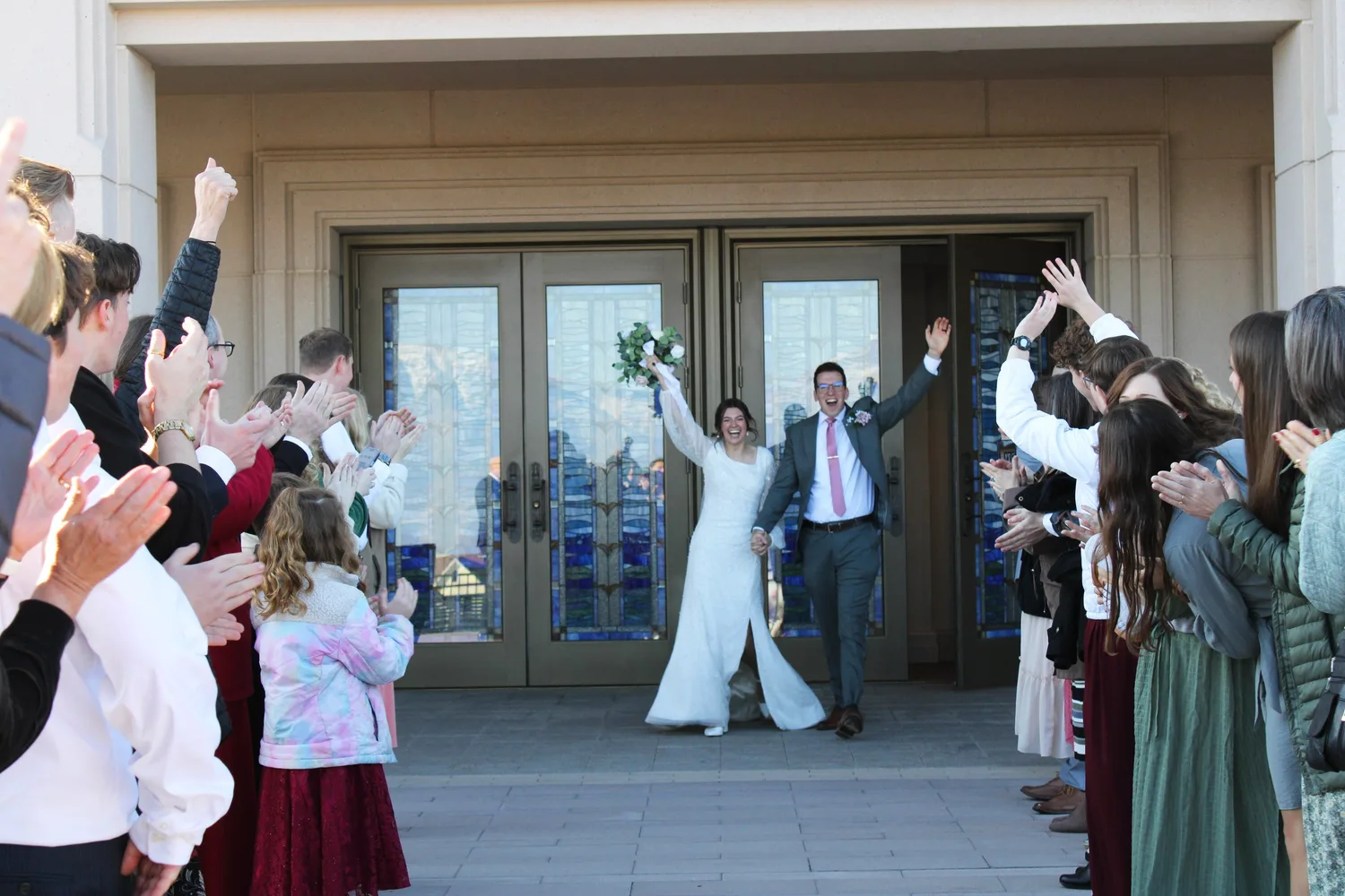 Newlyweds celebrating as they exit the temple through a line of cheering guests