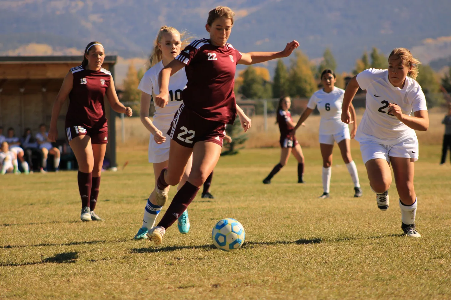 Girls' soccer player dribbling the ball upfield past defenders