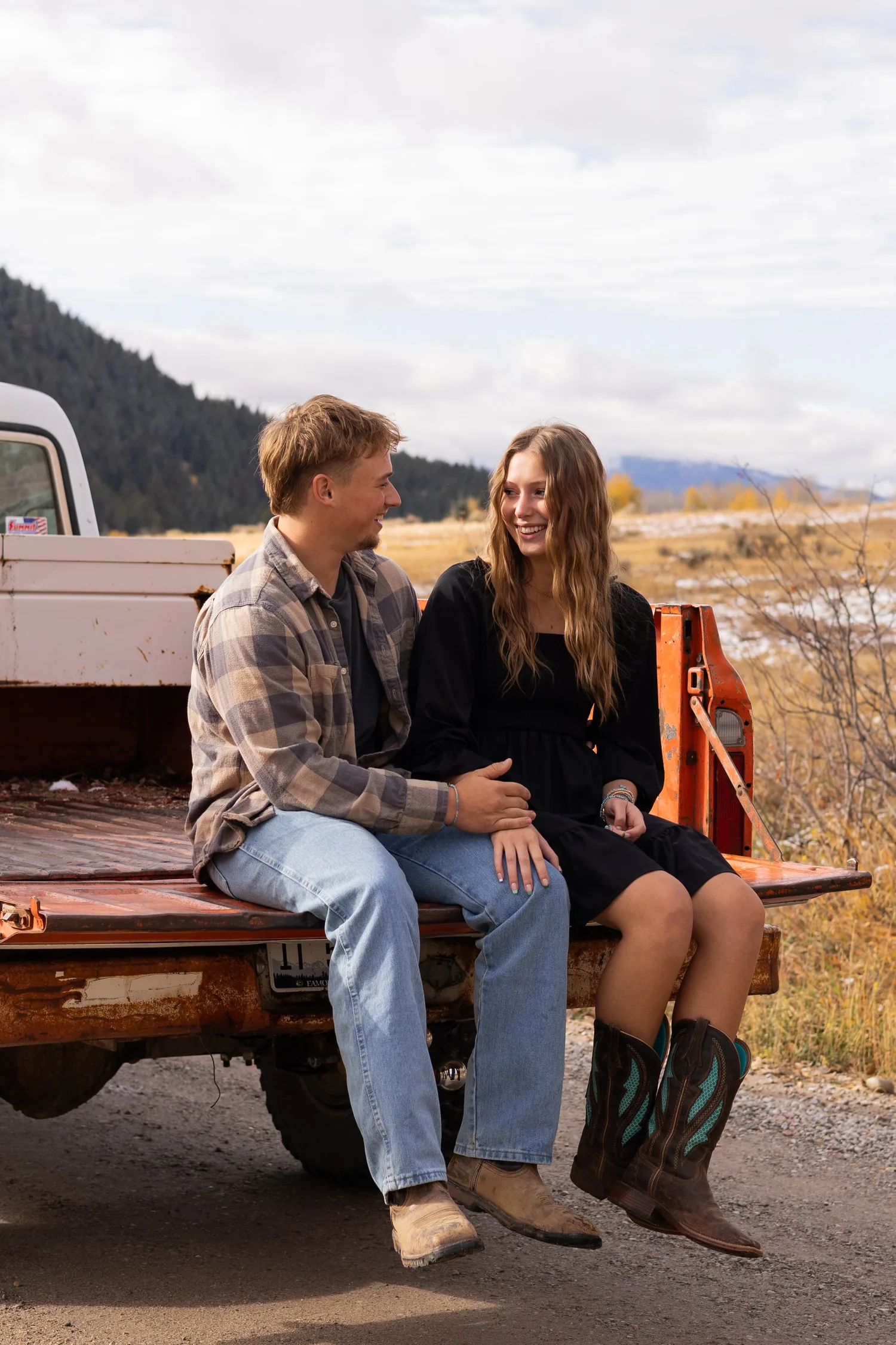 Couple sitting on the tailgate of a vintage pickup truck in the mountains